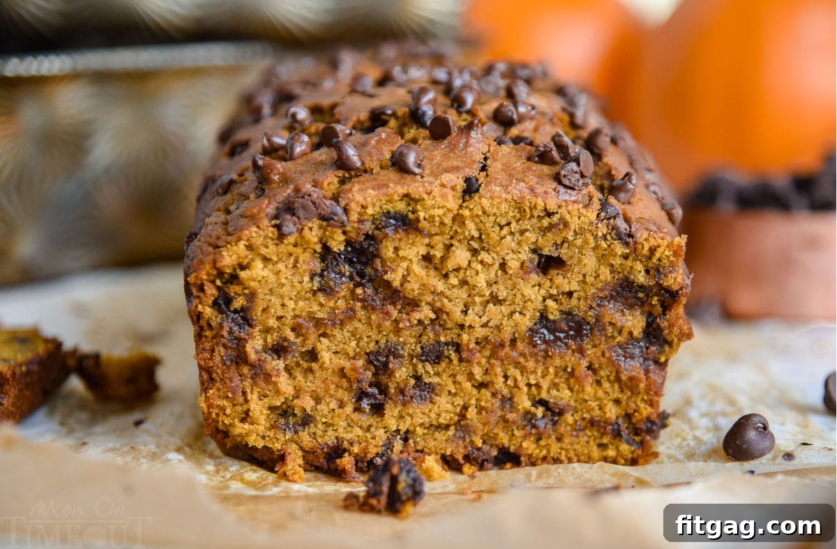 warm loaf of pumpkin bread with one slice removed sitting on parchment