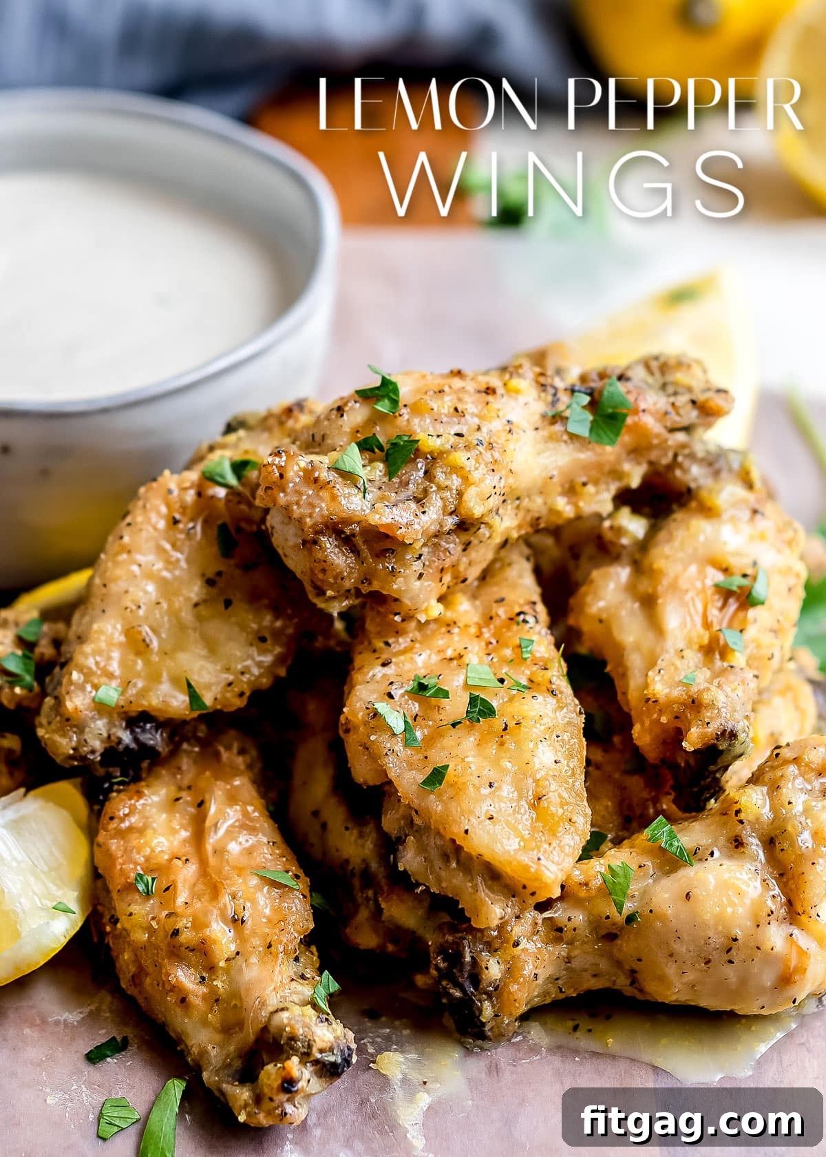 Irresistible Lemon Pepper Wings Baked or Air Fried 2 lemon pepper wings stacked in a pile with a bowl of ranch behind them and title overlay at the top