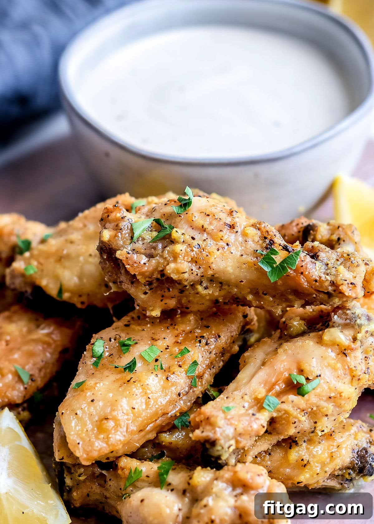 Irresistible Lemon Pepper Wings Baked or Air Fried 7 crispy baked chicken wings garnished with lemon pepper sauce and parsley small bowl of ranch in back