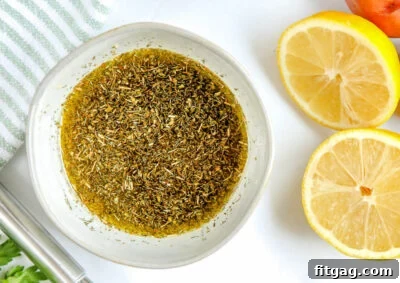 A small bowl of freshly mixed Greek chicken marinade, with whole and halved lemons on the side, ready to infuse flavor.