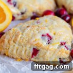 cranberry orange scone sitting on parchment paper with orange glaze drizzled on top