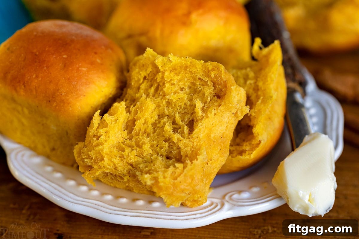 pumpkin dinner roll split in half on white plate