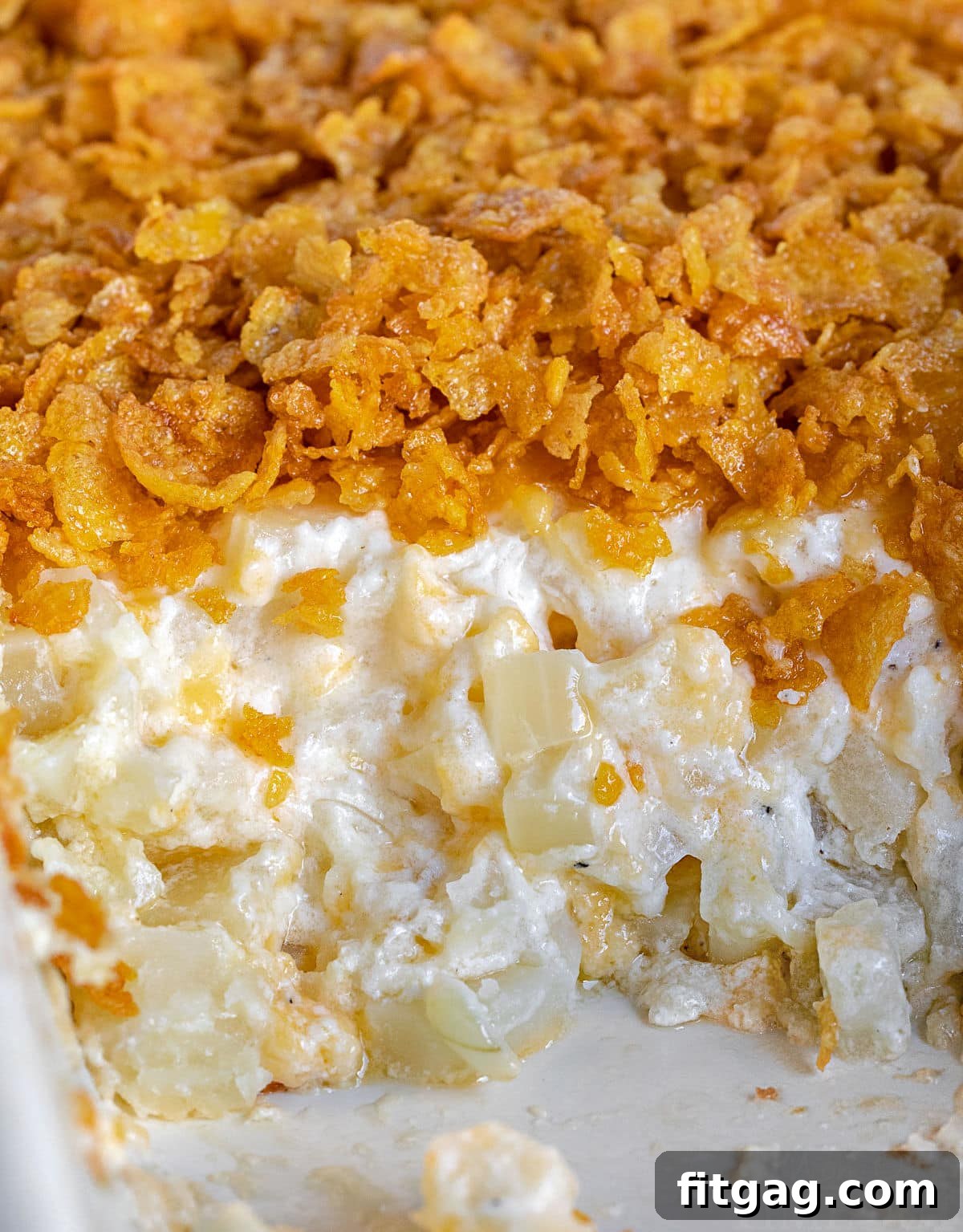 Close-up view of a large baking dish filled with golden-brown cheesy potatoes, showing the bubbly, rich texture and inviting crunchy topping.