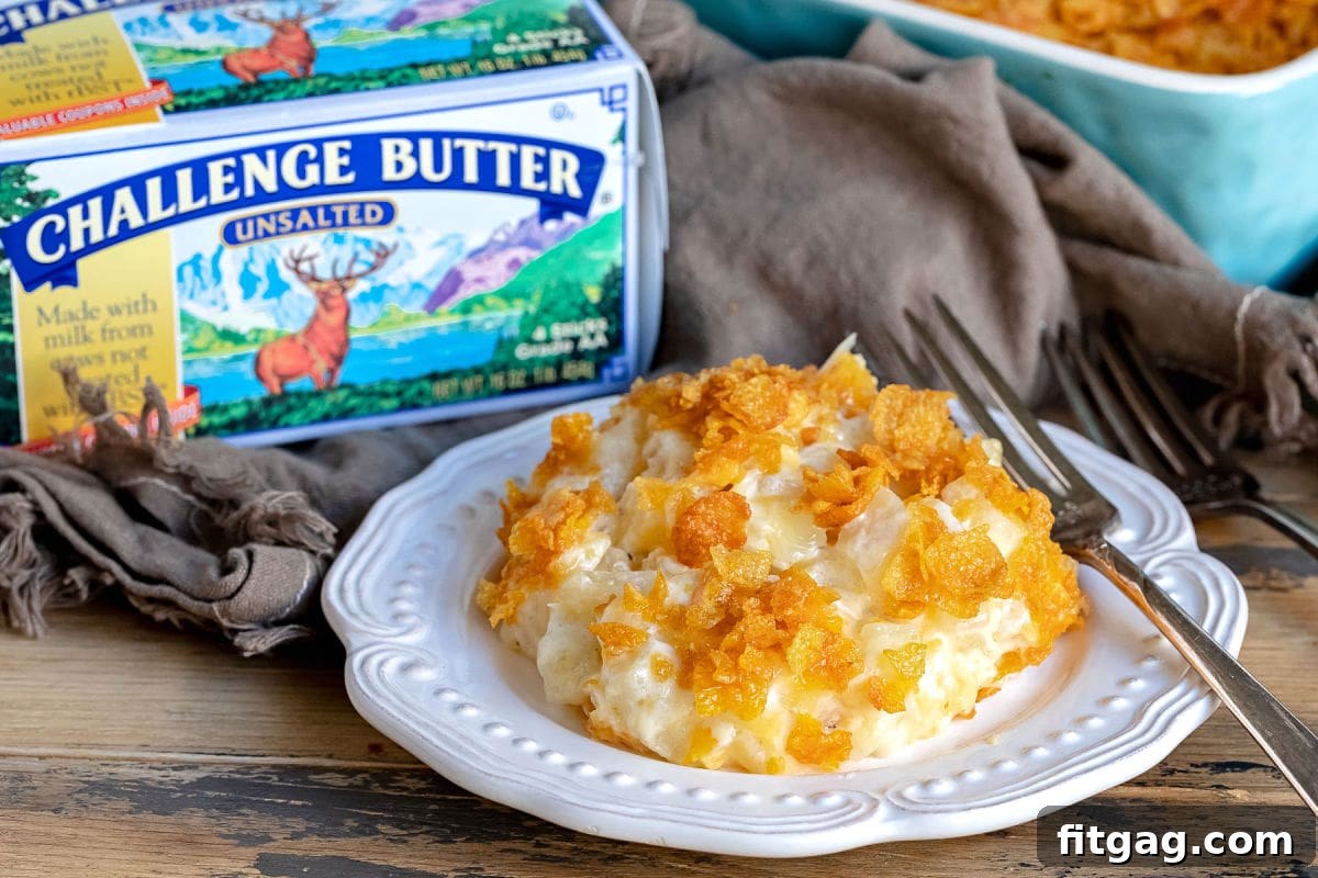 A delectable serving of cheesy potatoes on a pristine white plate, with a box of Challenge Butter visible in the background, hinting at the quality ingredients used.