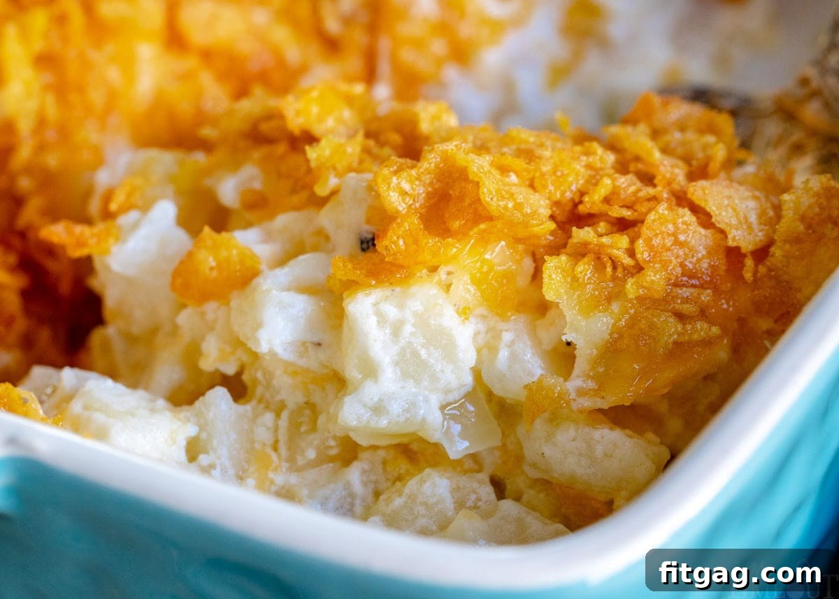 A large casserole dish brimming with perfectly baked funeral potatoes, featuring a golden, crunchy cornflake topping, ready to be served.
