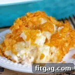 A small image of cheesy potatoes on a white plate with casserole dish in the background