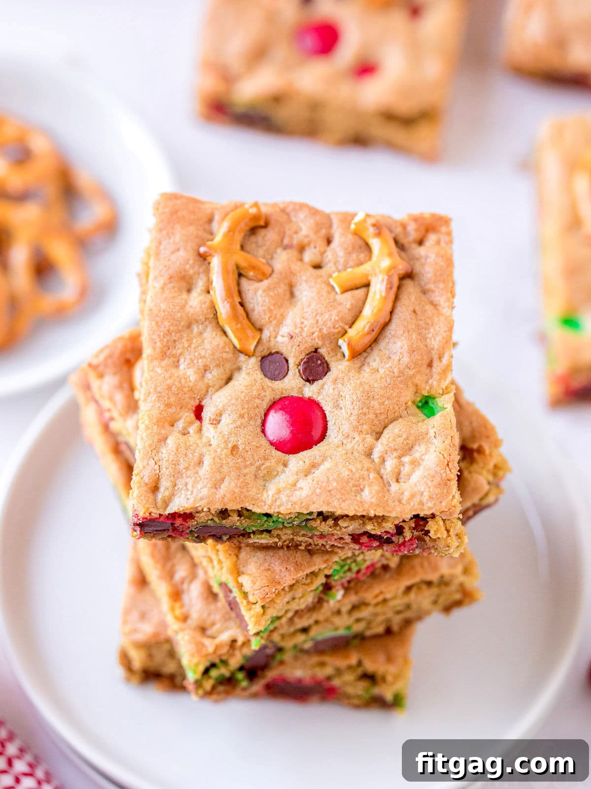 Magical Reindeer Cookie Bars 3 A top-down view of four Reindeer Cookie Bars, perfectly stacked on a clean white plate, highlighting their appealing texture and decorations.