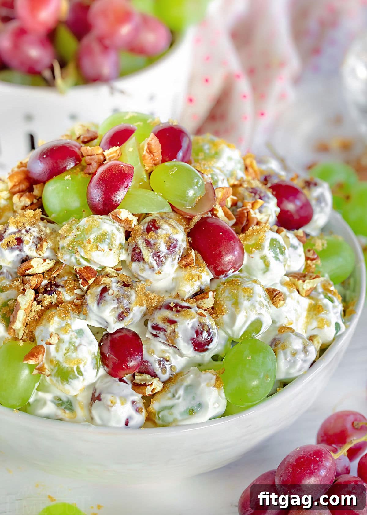 Creamy Grape Crunch 3 front view of creamy grape salad in white bowl with grapes scattered around
