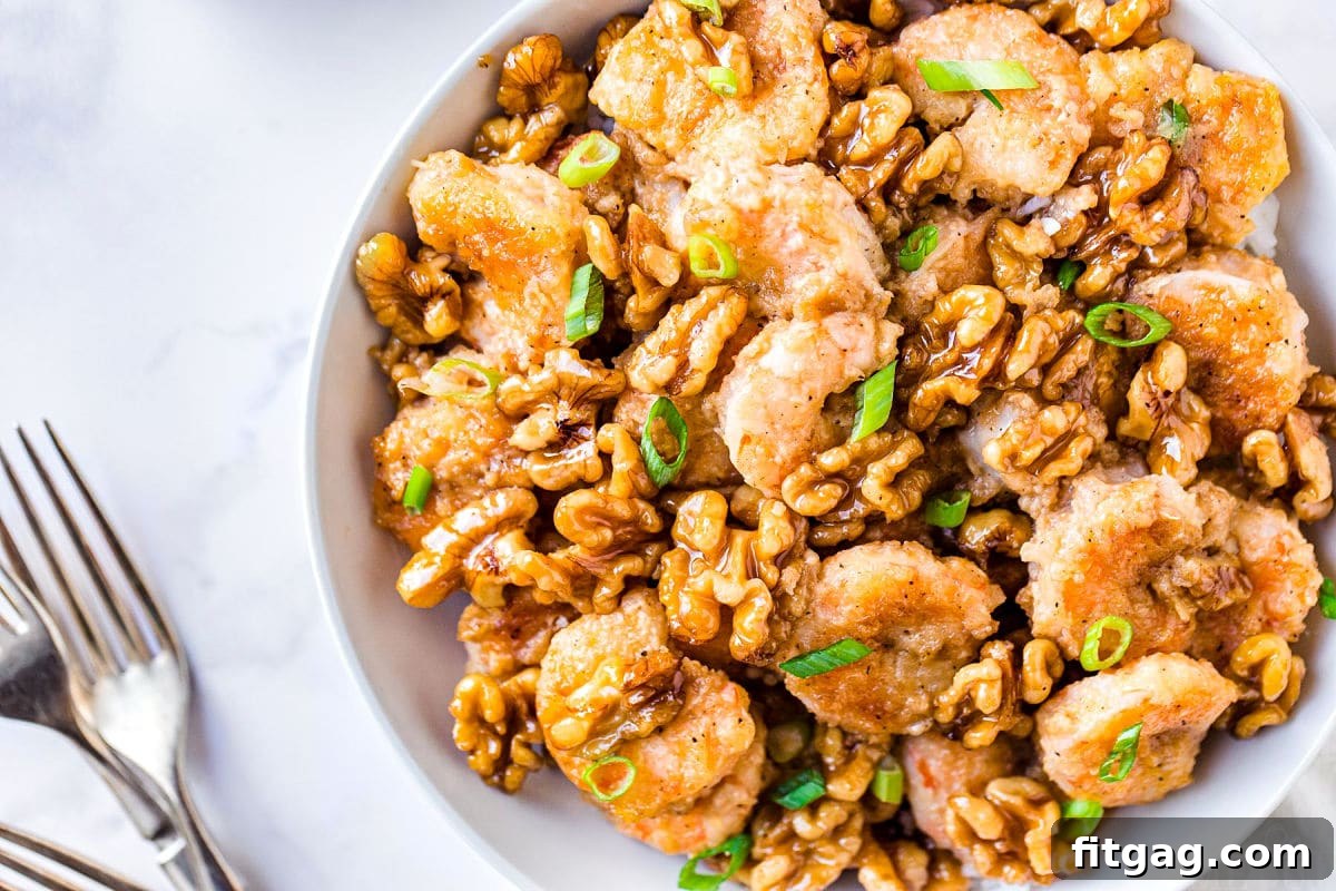 Top-down view of Honey Walnut Shrimp elegantly arranged in a white bowl, garnished with vibrant green onions, with serving forks positioned nearby.