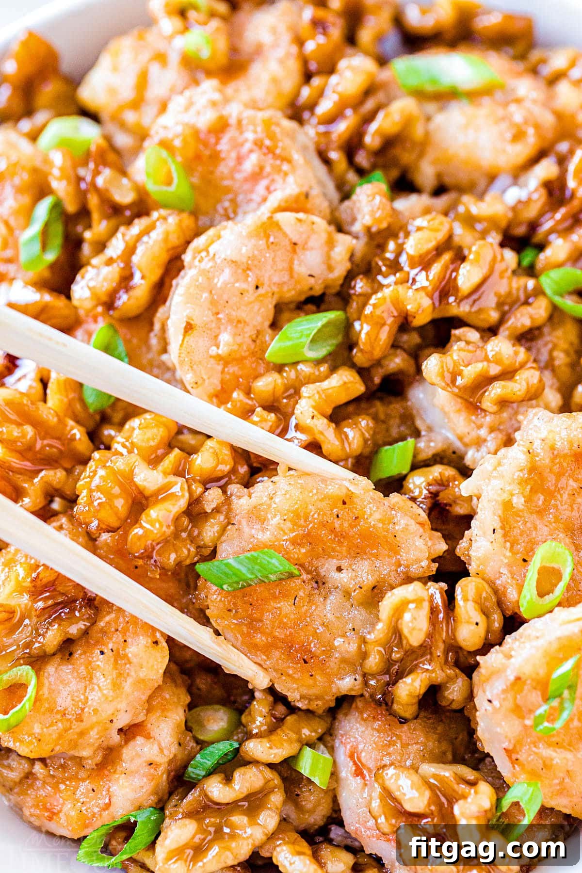 Close-up shot of Honey Walnut Shrimp being picked up with chopsticks, showing the crispy texture and creamy sauce.