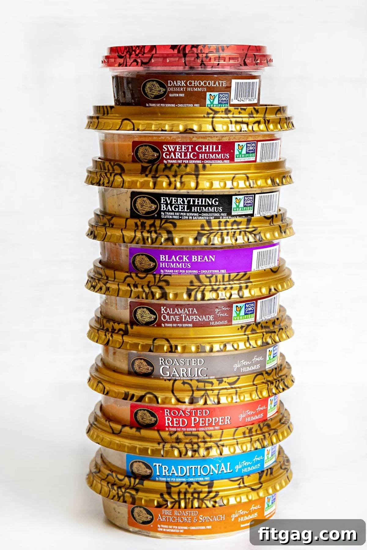 Various containers of Boar's Head hummus stacked neatly on a white surface, showcasing different flavors available for the stuffed veggie tray.