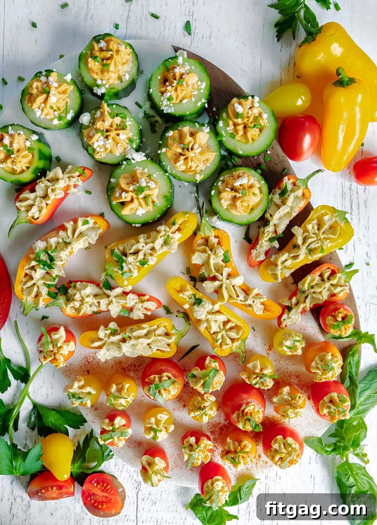 A vibrant top-down shot of the finished hummus stuffed vegetables, artfully arranged and generously topped with a variety of fresh herbs, ready to be served as an appetizer.