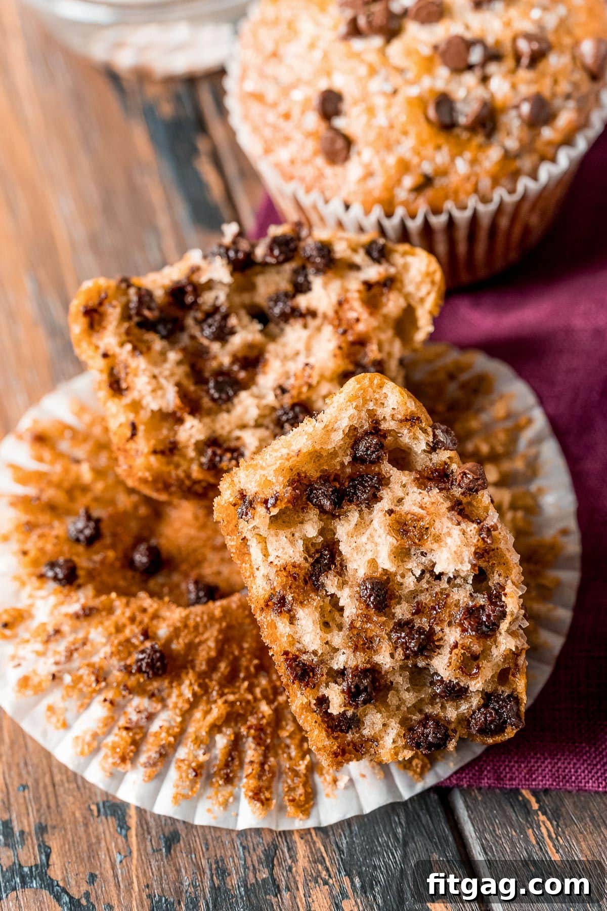 Effortless Chocolate Chip Muffins 3 A perfectly split chocolate chip muffin, still nestled in its paper liner, revealing its moist interior and generous distribution of chocolate chips.