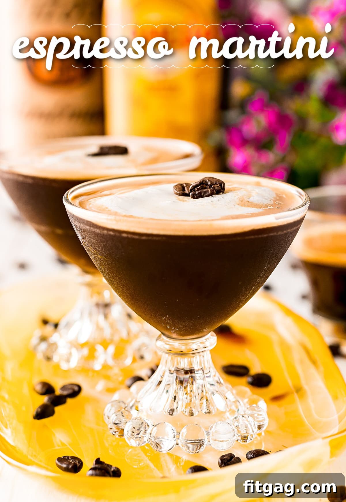 two espresso martini in fancy martini glass on yellow tray with title overlay at top of image and bottles in background