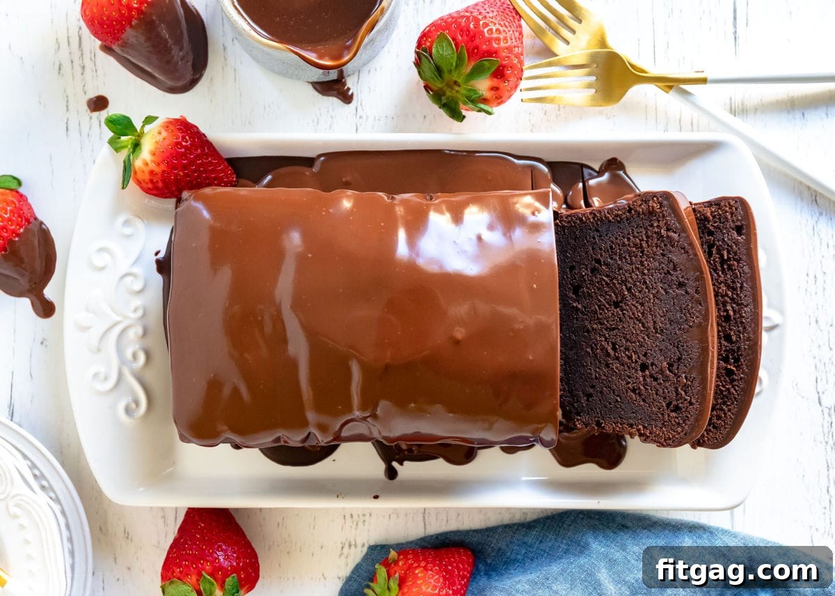 A pristine white tray showcasing a freshly baked chocolate pound cake adorned with a glossy chocolate ganache glaze, with two inviting slices already cut and ready to be served, highlighting its rich and decadent appearance.