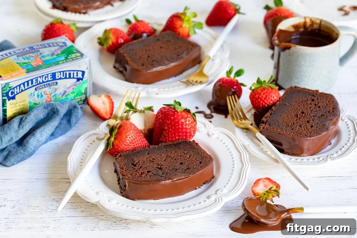 Beautifully sliced chocolate pound cake, generously drizzled with a rich chocolate glaze and garnished with fresh strawberries, served on individual white plates, highlighting its gourmet appeal.