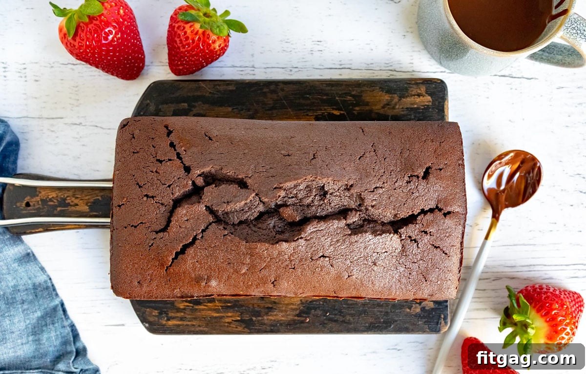 A perfectly baked chocolate pound cake, cooling on a wooden board, showcasing its rich color and inviting texture, anticipating the final glaze and serving.