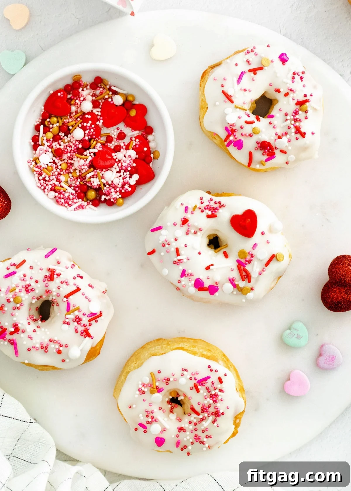 Four air fryer donuts elegantly decorated for Valentine's Day, arranged on a round marble surface.