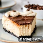 piece of cheesecake on pottery plate topped with ganache and frosting