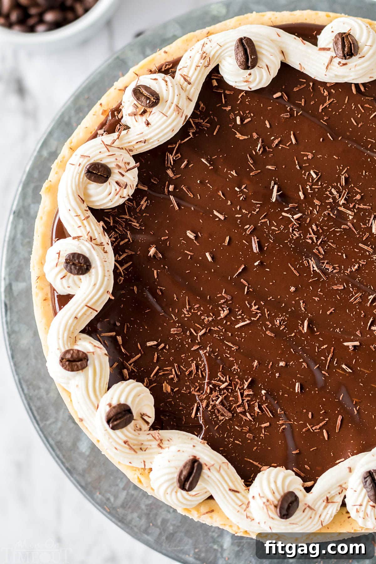 A top-down view of an entire espresso cheesecake, beautifully garnished and presented on a sleek metal cake stand, ready to be served.
