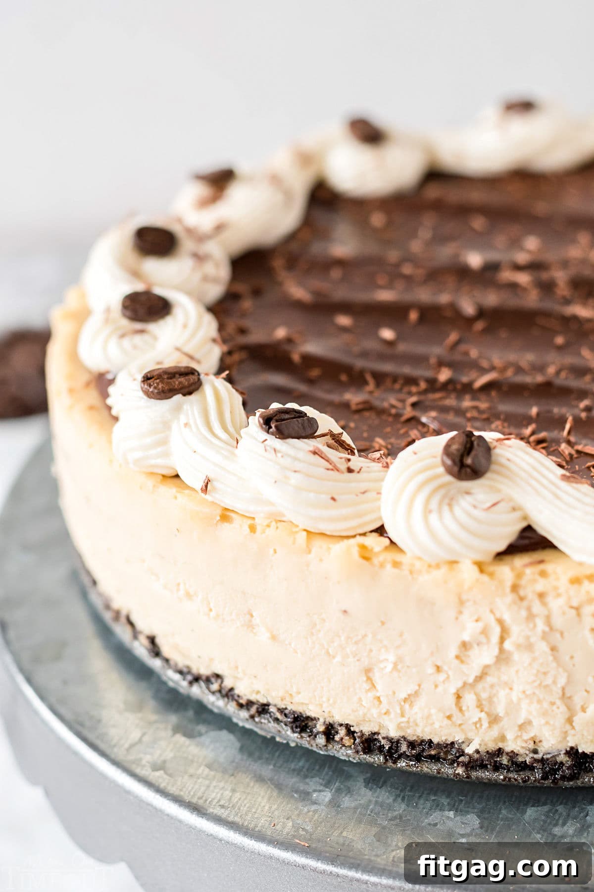 Close-up of espresso cheesecake adorned with intricate cream cheese frosting piping, rich chocolate ganache, and decorative espresso beans, showcasing its elegant finish.