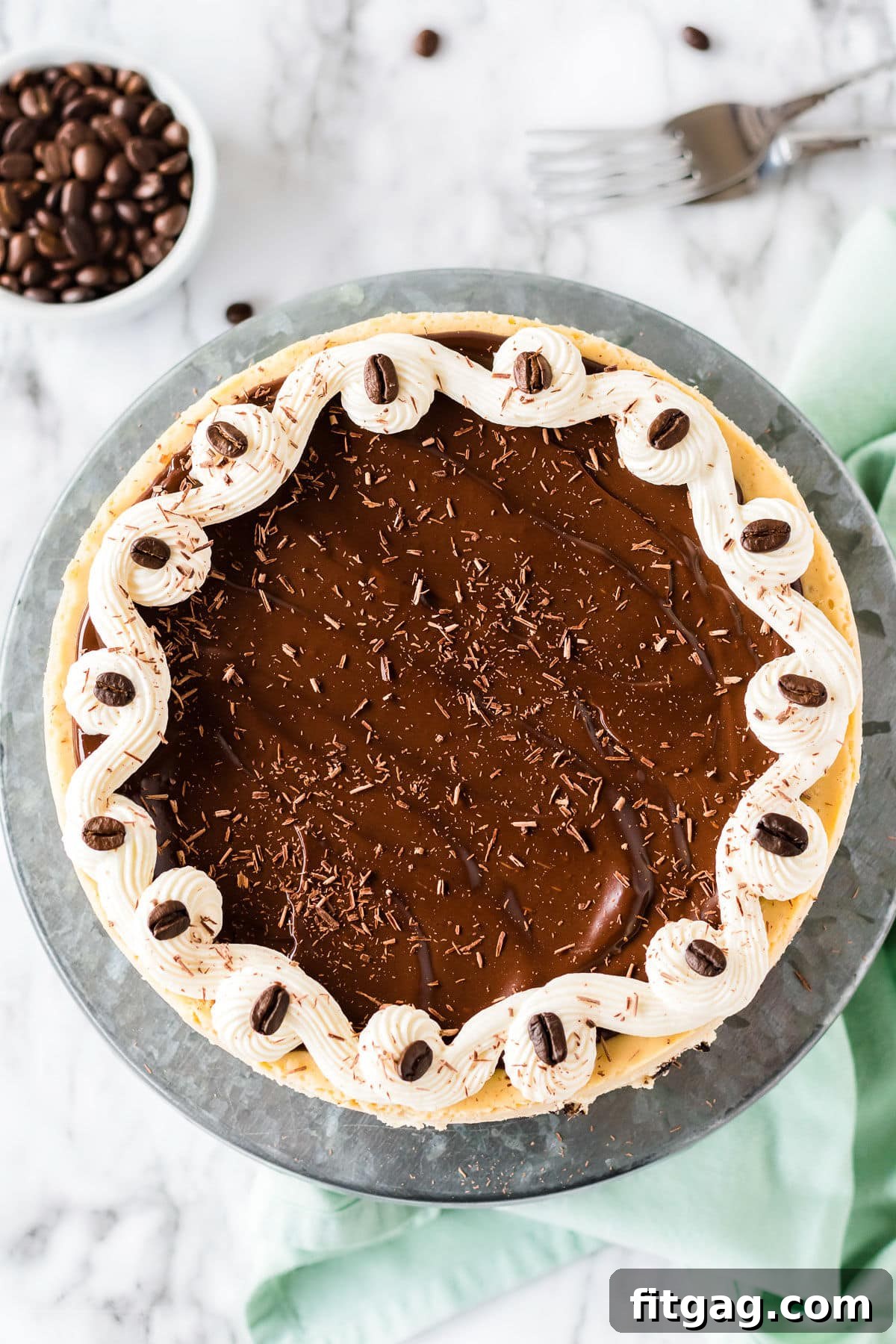 A close-up view of a whole espresso cheesecake, featuring a smooth ganache topping beautifully scattered with chocolate shavings, ready for slicing.