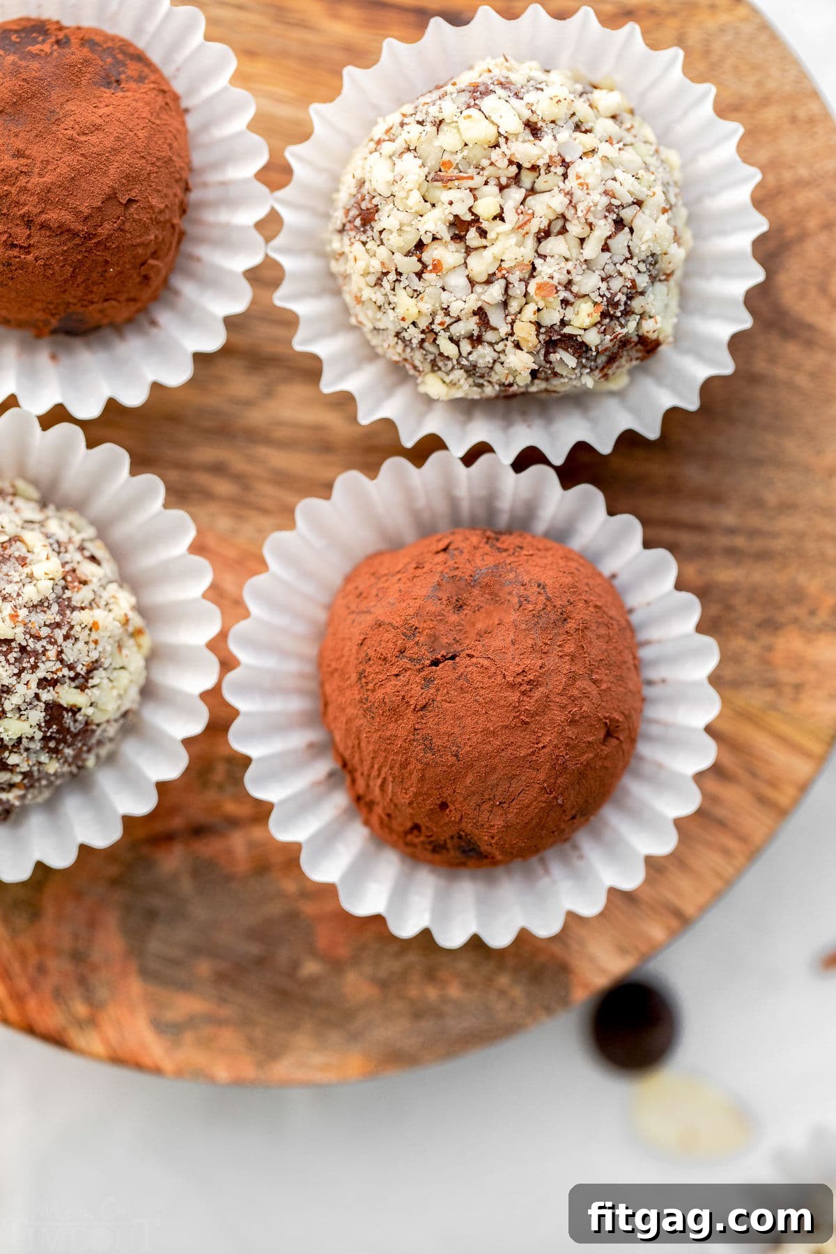 four truffles sitting on wood board each in individual white paper cups.