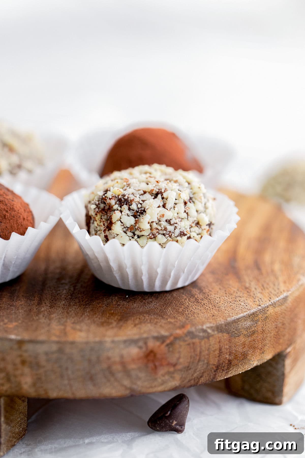 chocolate truffle coated in almonds in white paper cup on wood board