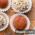 Four truffles sitting on a wooden board, each in individual white paper cups.