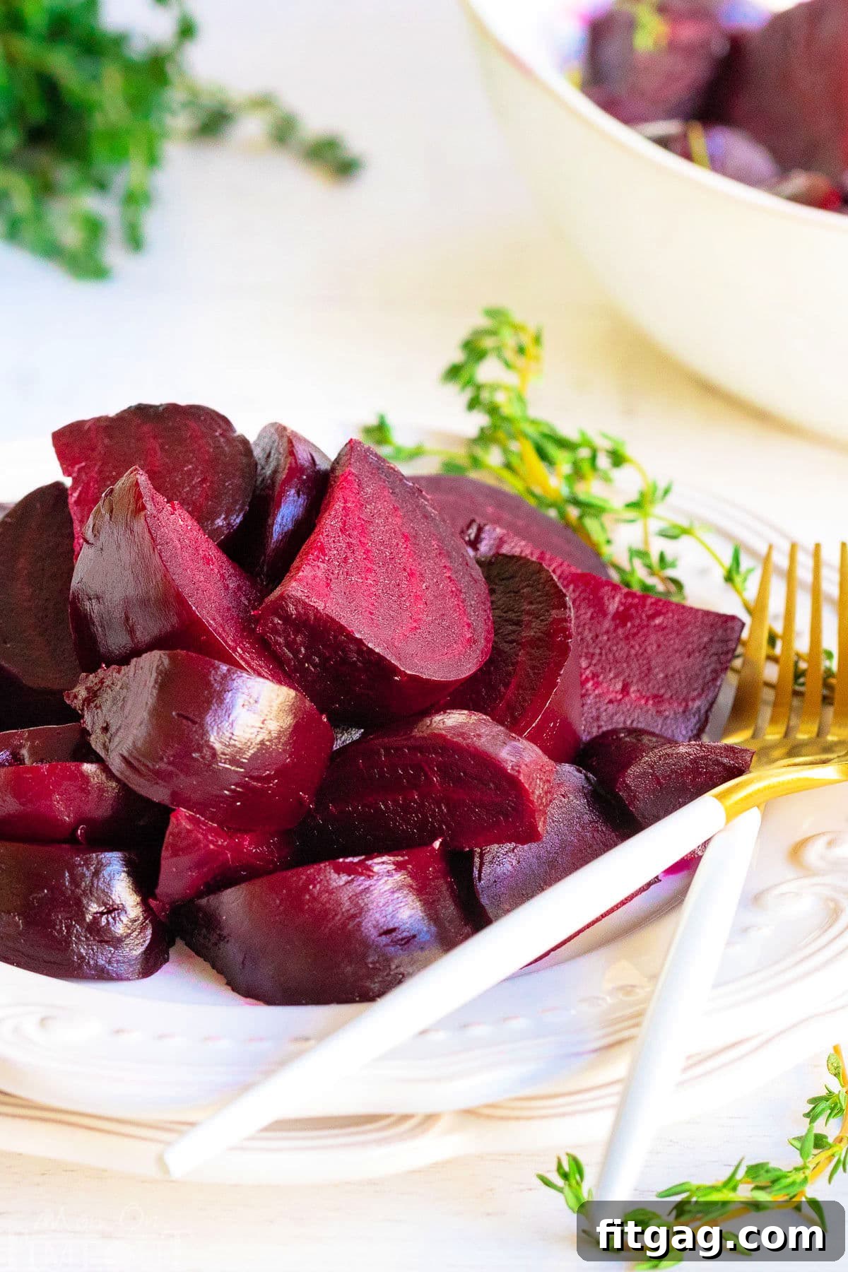 Effortlessly Delicious Roasted Beets 7 roasted beets cut up and arranged on white plate with thyme in background.