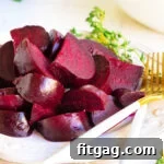 roasted beets cut up and arranged on white plate with white and gold forks and thyme in background.