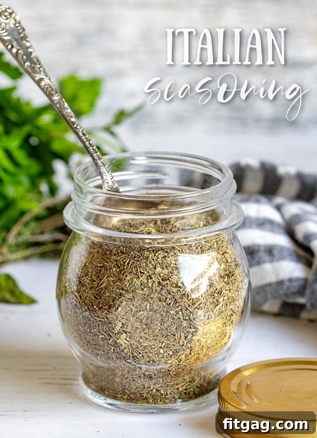 Homemade Italian seasoning in a small glass jar with a spoon, ready to use.