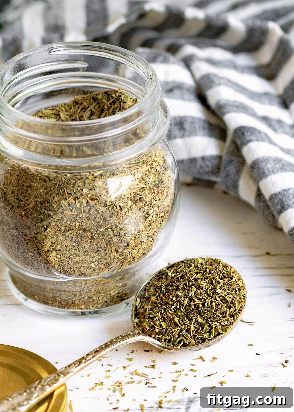 A spoonful of Italian seasoning mix held in front of a jar.