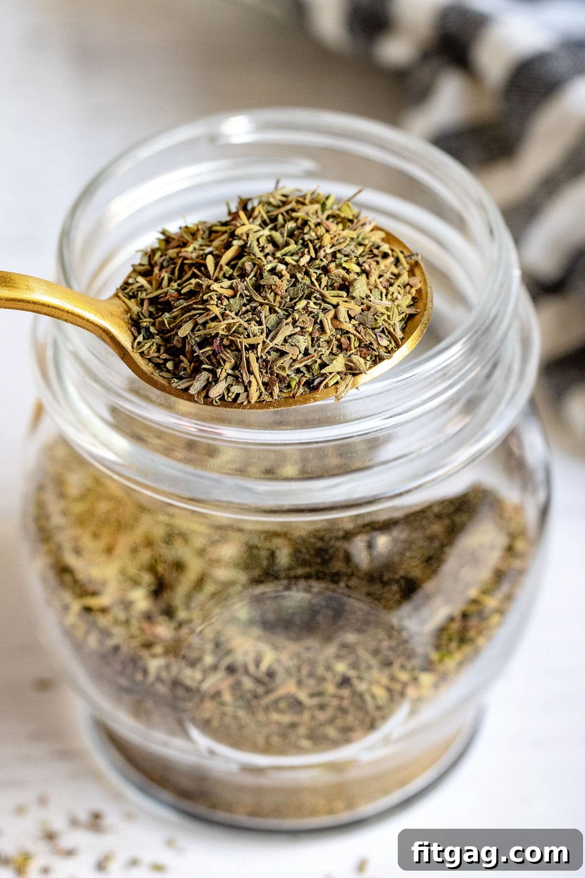 A spoonful of homemade Italian seasoning held over a full jar, ready for use.