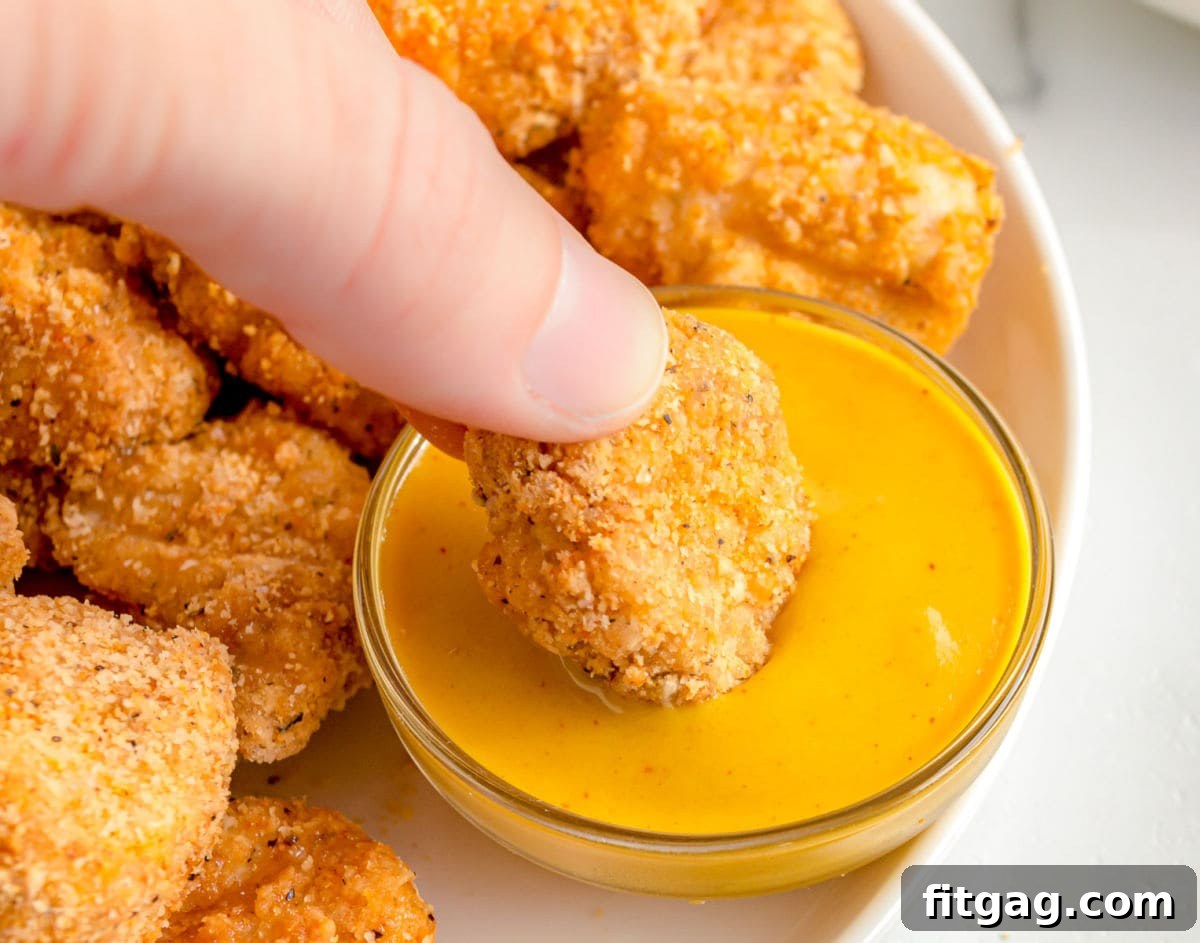 chicken nuggets being dipped in honey mustard sauce.