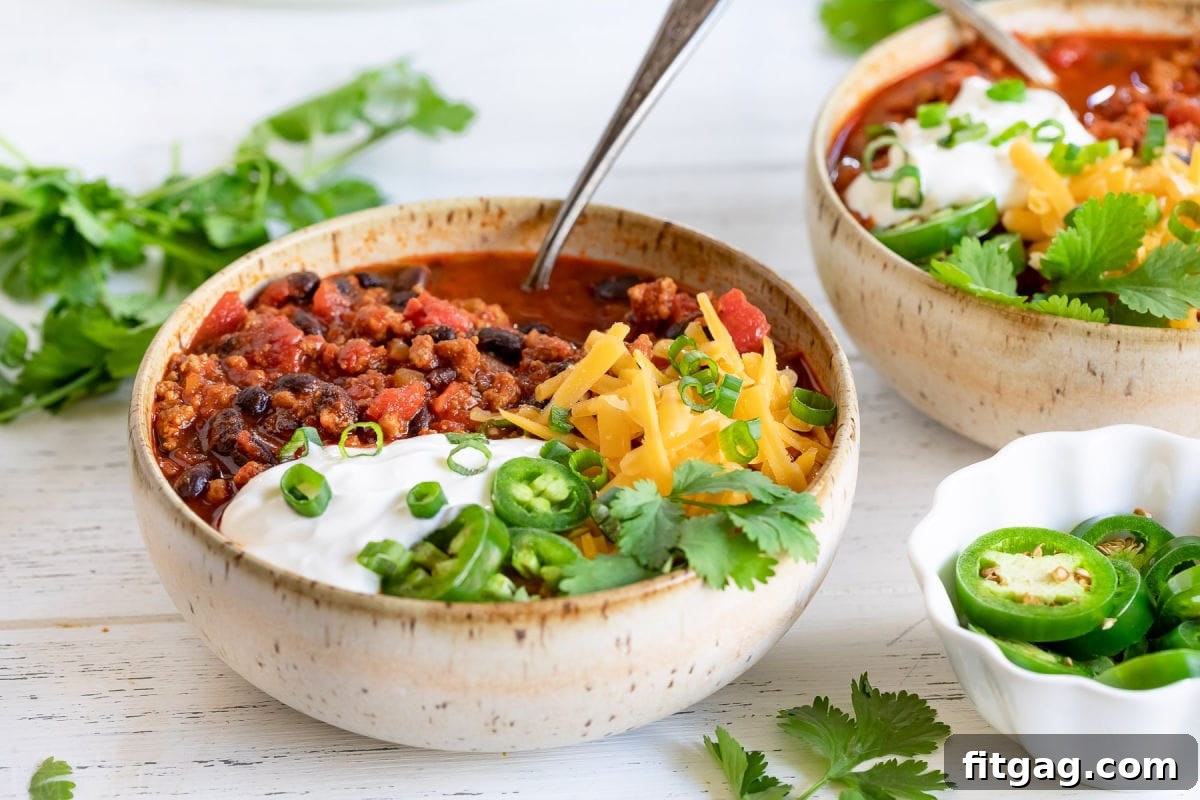 two bowls of chili loaded with toppings.