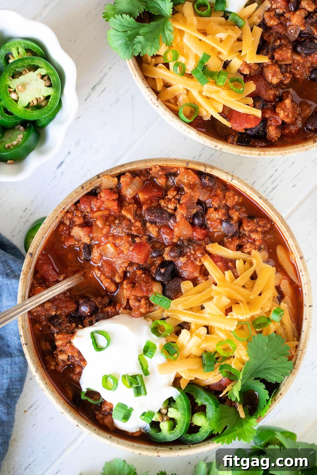 2 bowls of turkey chili with lots of toppings.