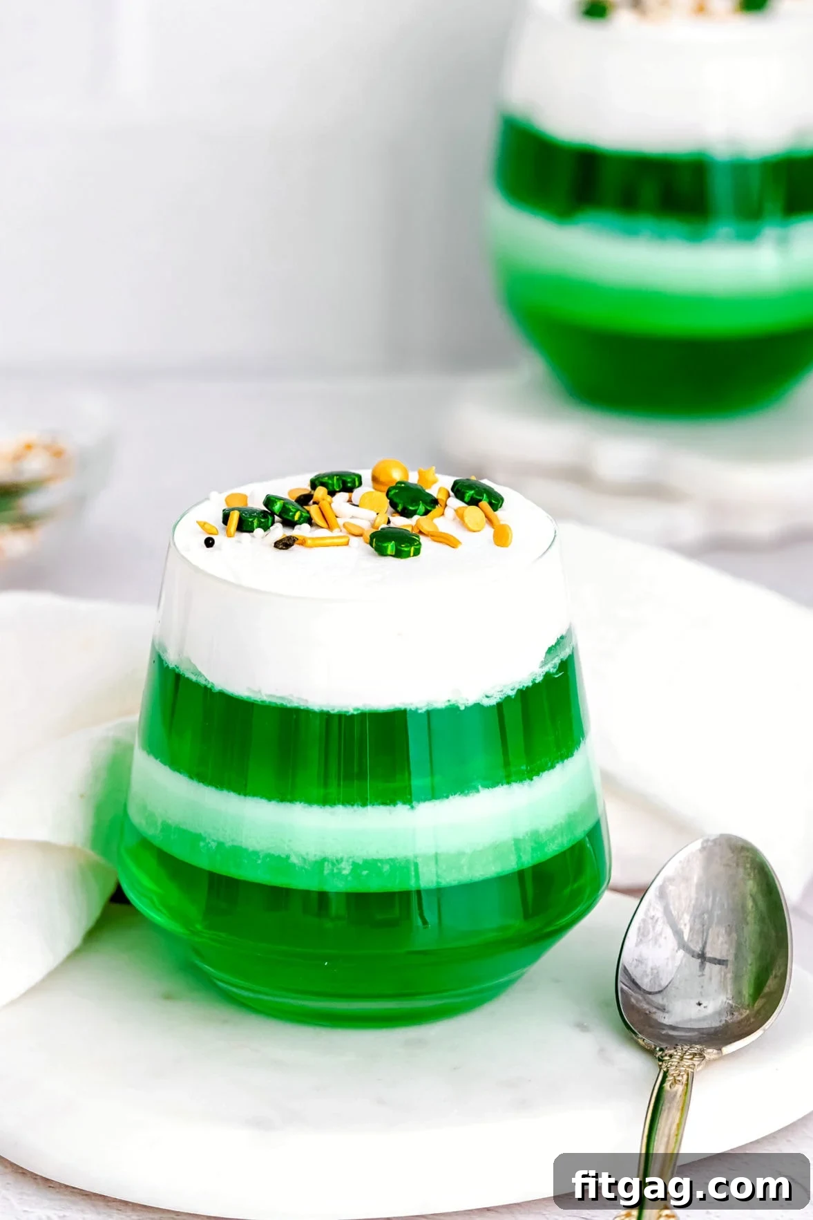 Layered green and white jello cups neatly arranged on a marble surface, ready for serving.