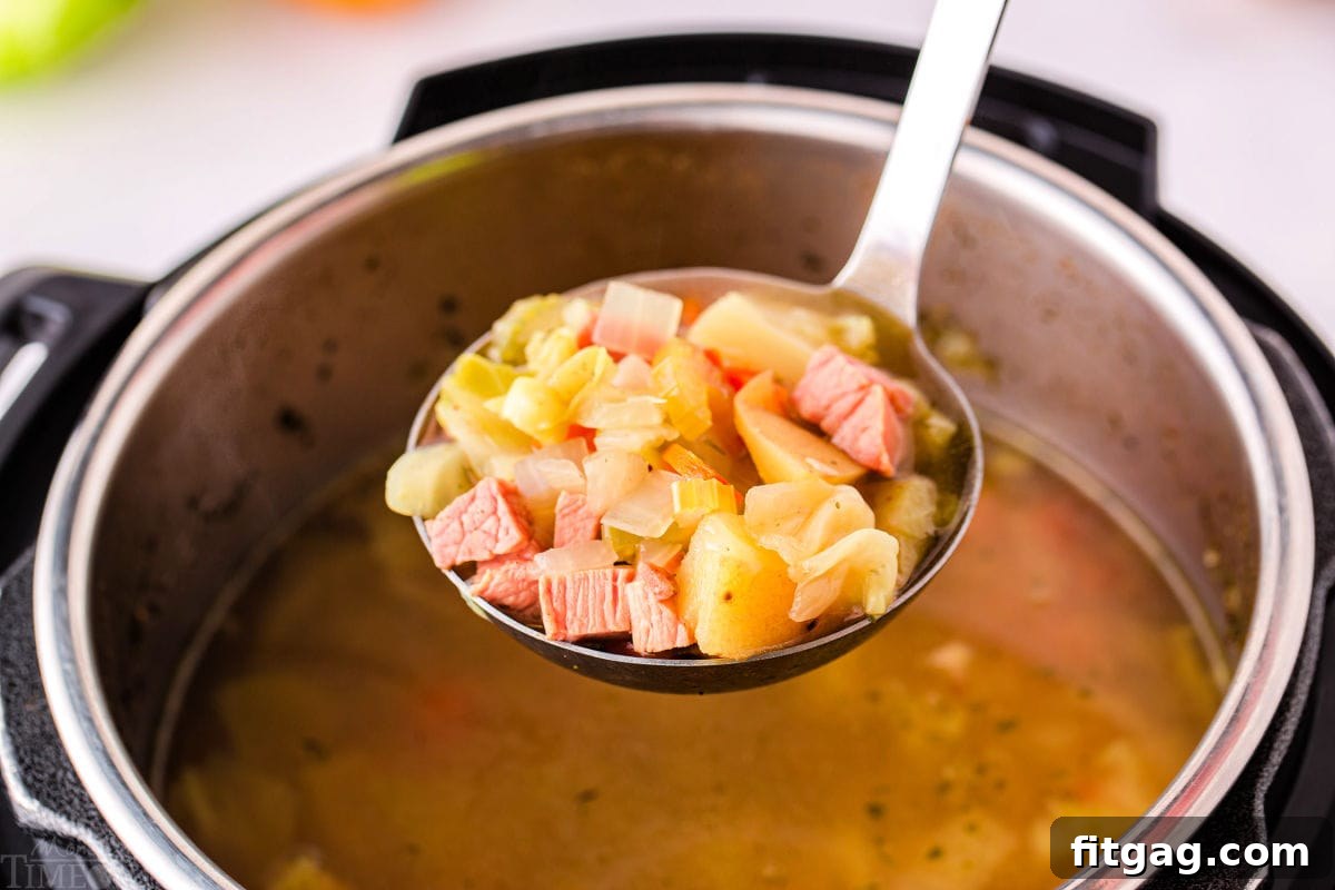 A ladle lifts a generous portion of flavorful ham and cabbage soup from an Instant Pot, ready to be served.