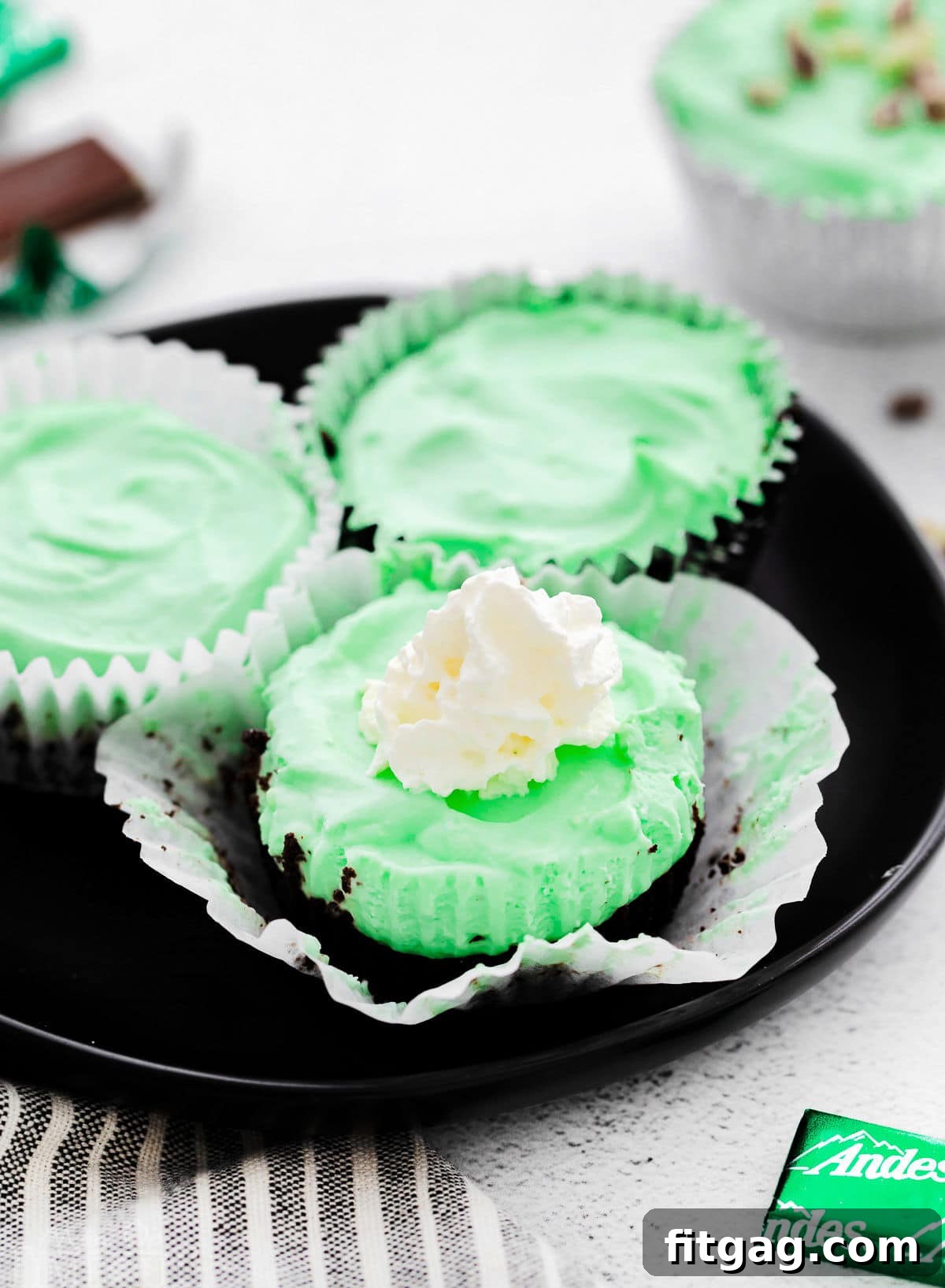 three grasshopper mini cheesecakes on black plate.