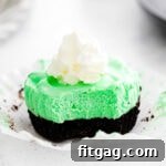 grasshopper mini cheesecake unwrapped with whipped cream on top and sitting on white surface