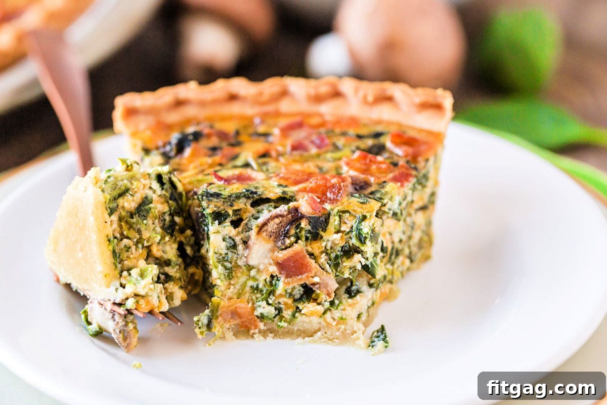 A delectable piece of spinach mushroom quiche, with a bite taken, showcasing its creamy interior and golden crust on a white plate.
