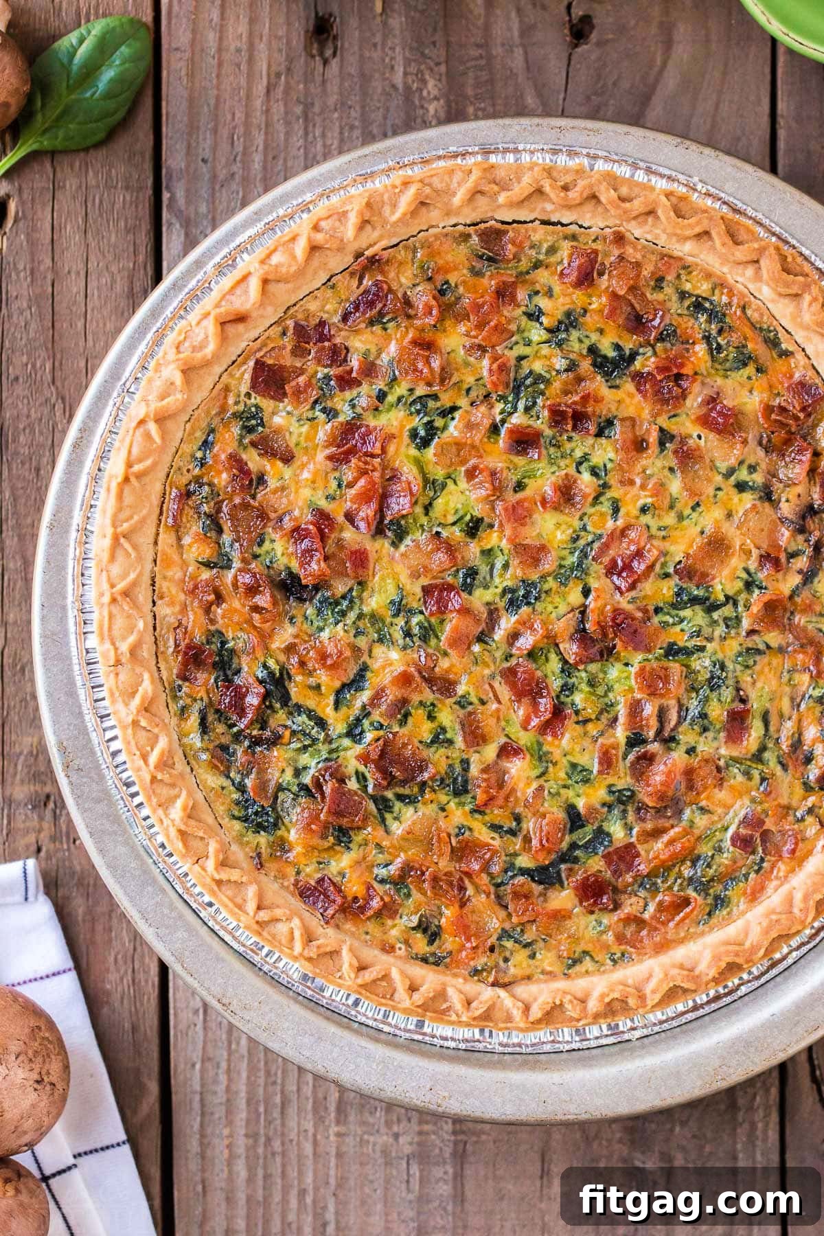 A stunning top-down view of a whole, freshly baked spinach quiche, perfectly golden and inviting, resting on a warm wooden surface.