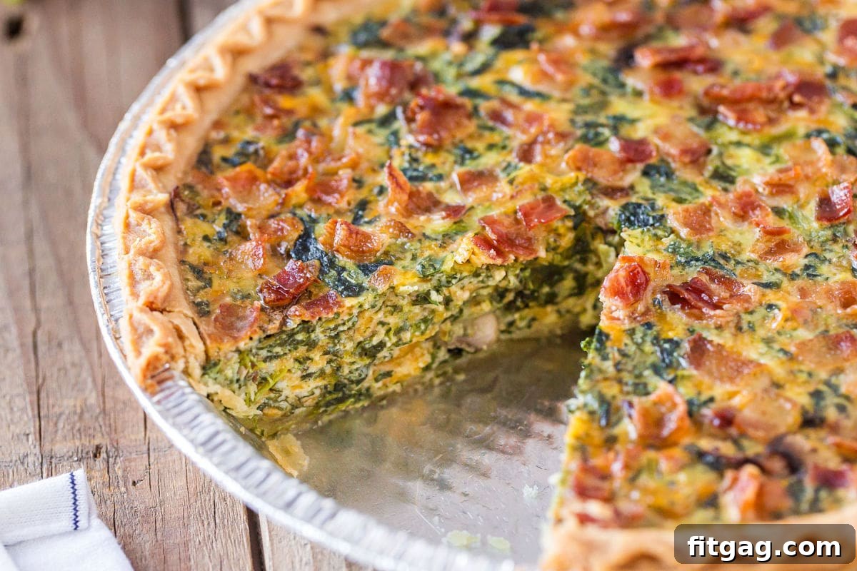 A perfectly baked spinach quiche recipe with a single, inviting slice removed, highlighting its rich, creamy filling and golden crust.