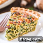 A perfect slice of spinach quiche, rich and creamy, served on a white plate, showcasing its golden crust and vibrant filling.