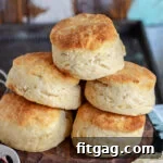 Golden brown Angel Biscuits stacked high on a wood board.