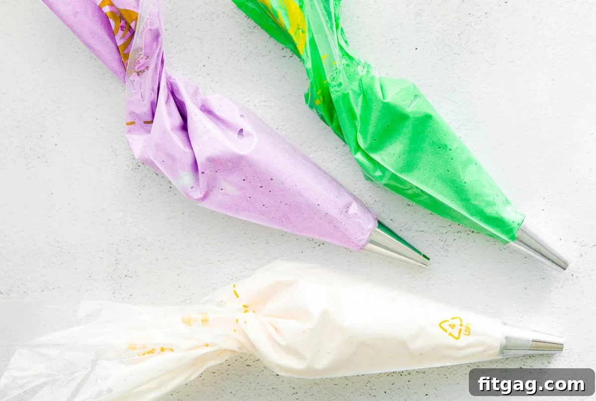 Three piping bags filled with colored macaron batter.