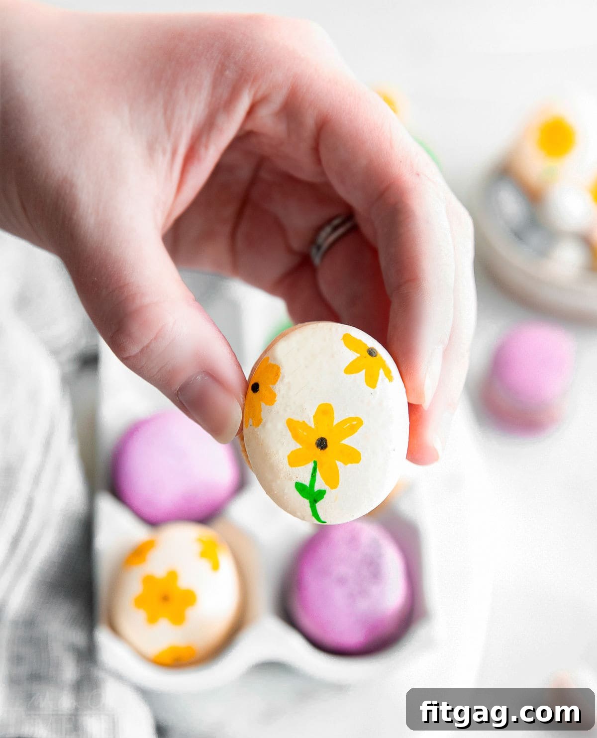 Hand-painted macaron being held.