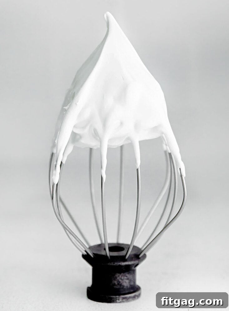 Egg whites beaten to stiff peaks shown on a whisk attachment.