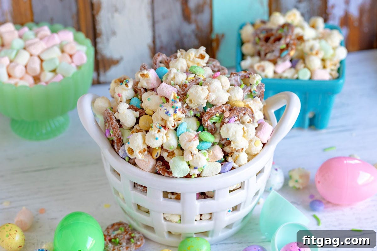 Hoppy Easter Snack Blend 4 A large serving of Bunny Bait Easter Snack Mix featuring popcorn, mini pretzels, and colorful marshmallows in a white bowl.